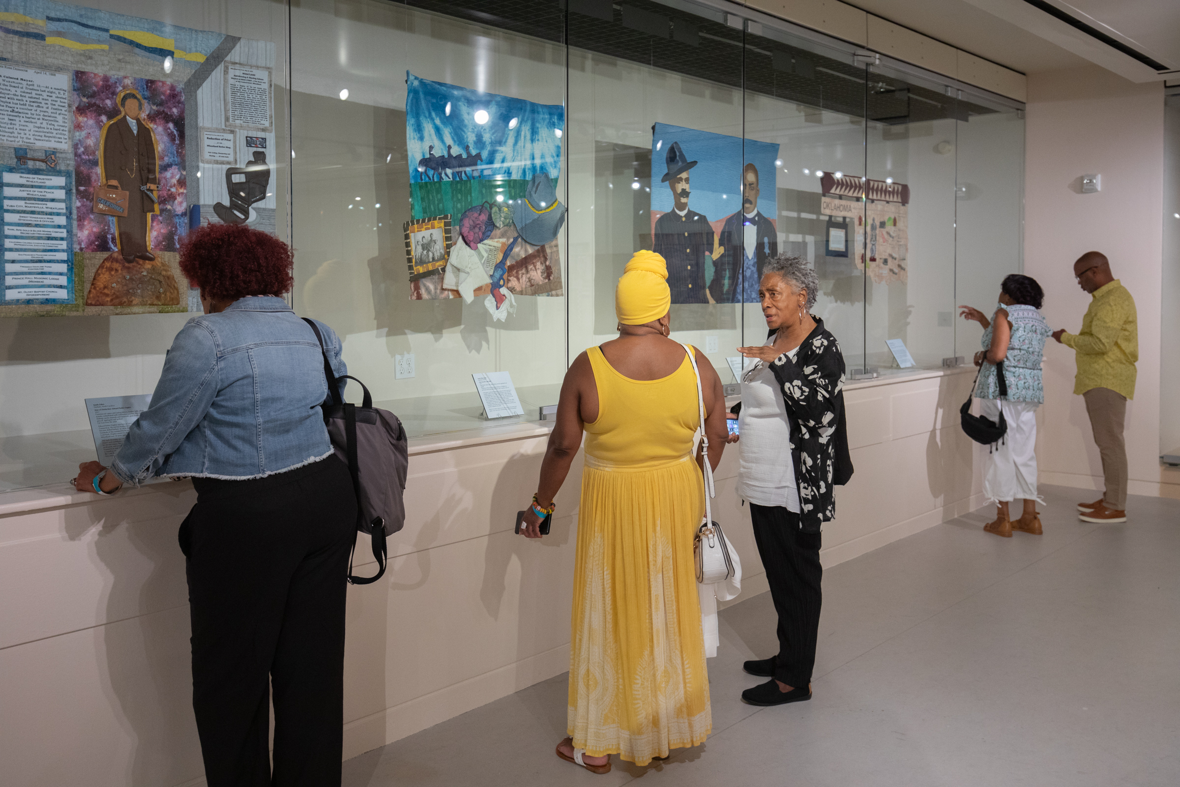 Visitors look at pictorial quilts in Black Pioneers exhibit