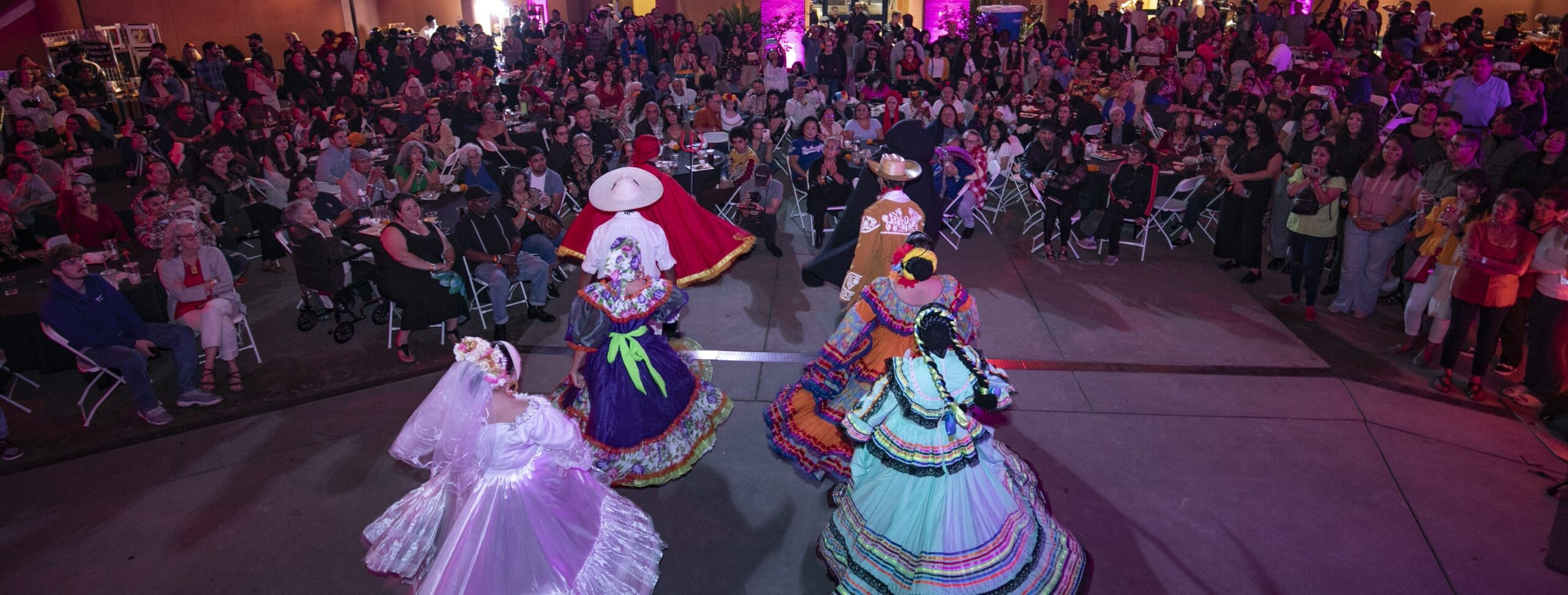 dancers perform in big, flowy dresses before a large audience