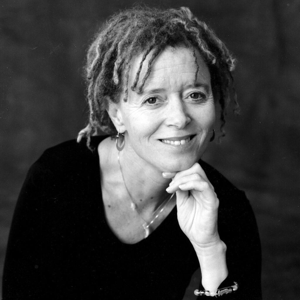 Headshot of a smiling Anne Lamott with her chin gently resting on her fingers.