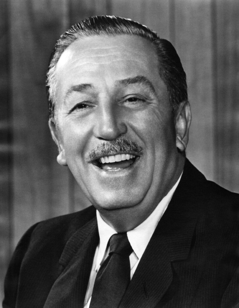 Headshot of a joyful Walt Disney wearing a suit and tie.