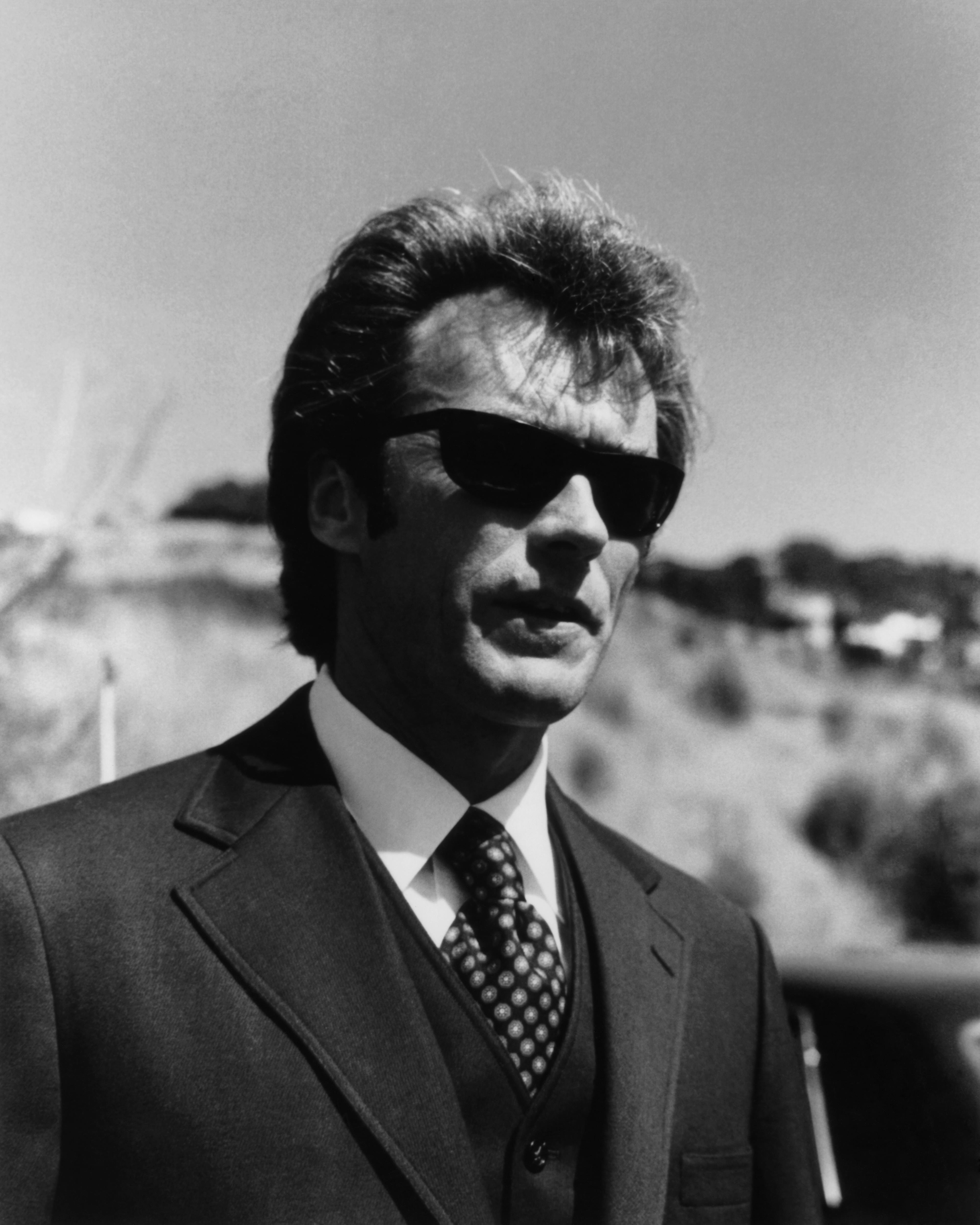 Clint Eastwood outside with a two-piece suit and sunglasses.