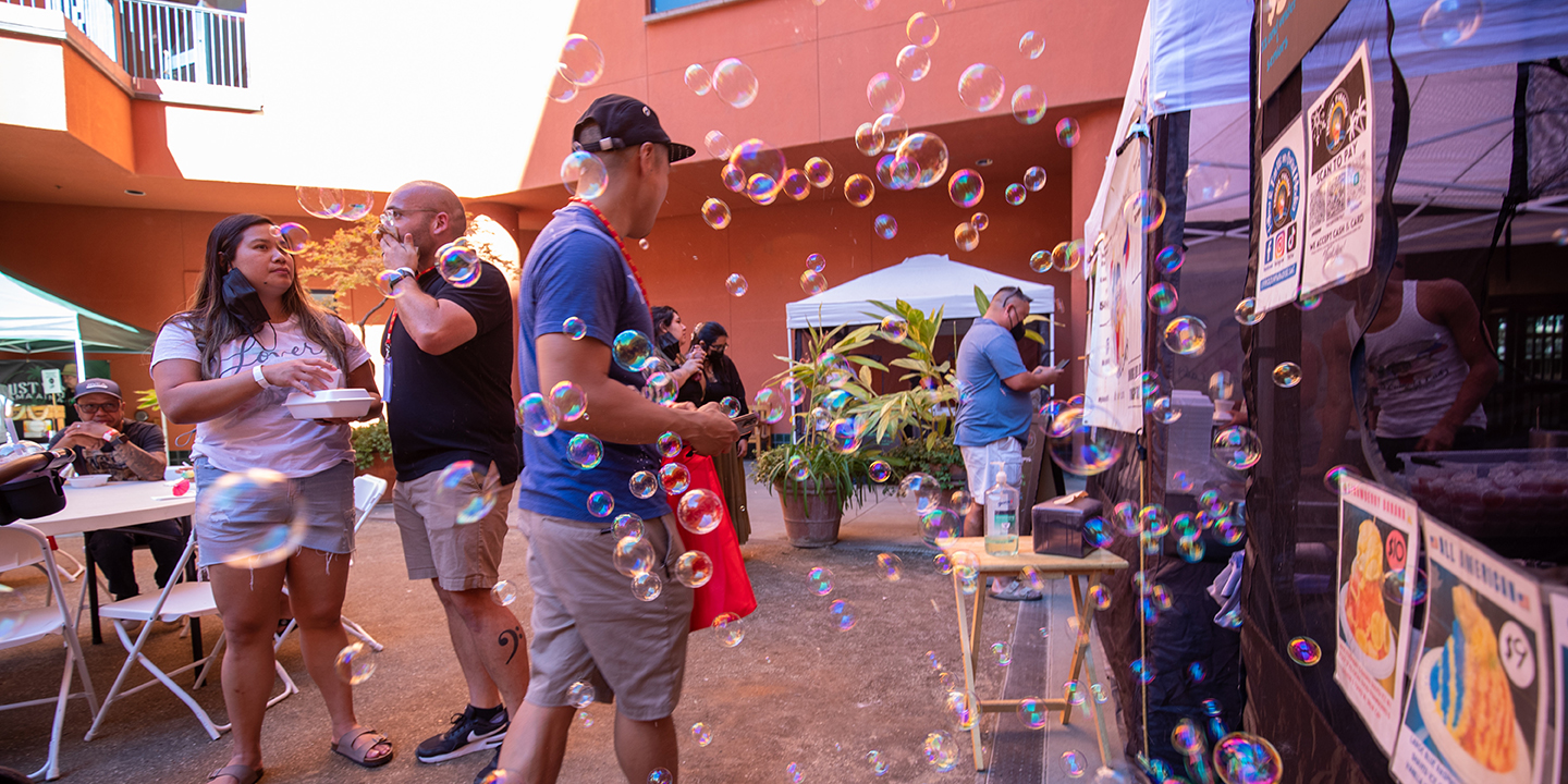 Bubbles float through the air as visitors enjoy a street food market in the courtyard.