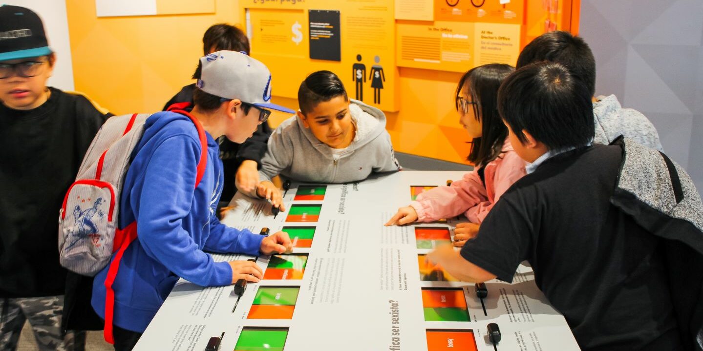 Students using an interactive table in the Women Inspire exhibit.
