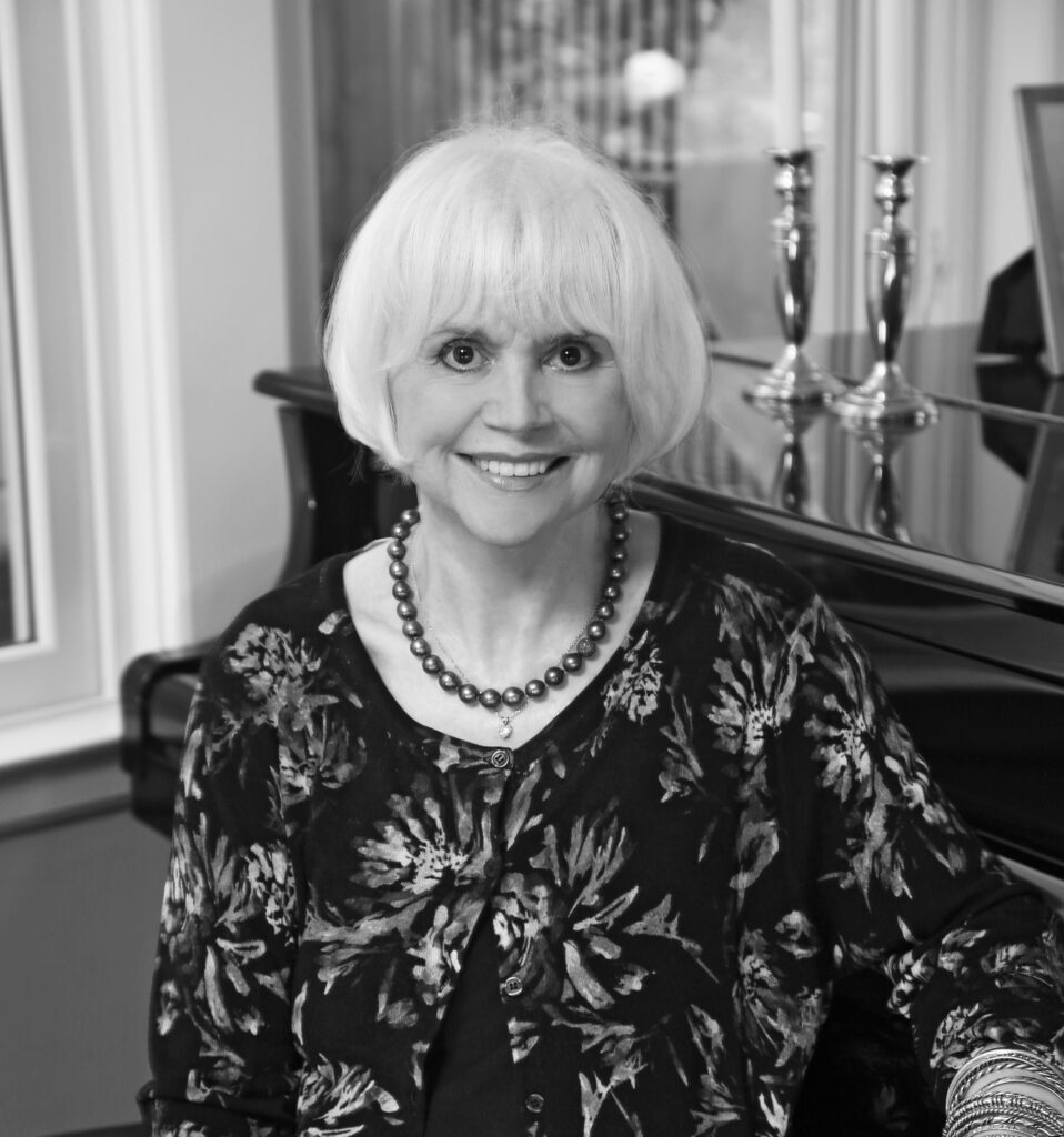 Linda Ronstadt poses warmly at her piano bench.