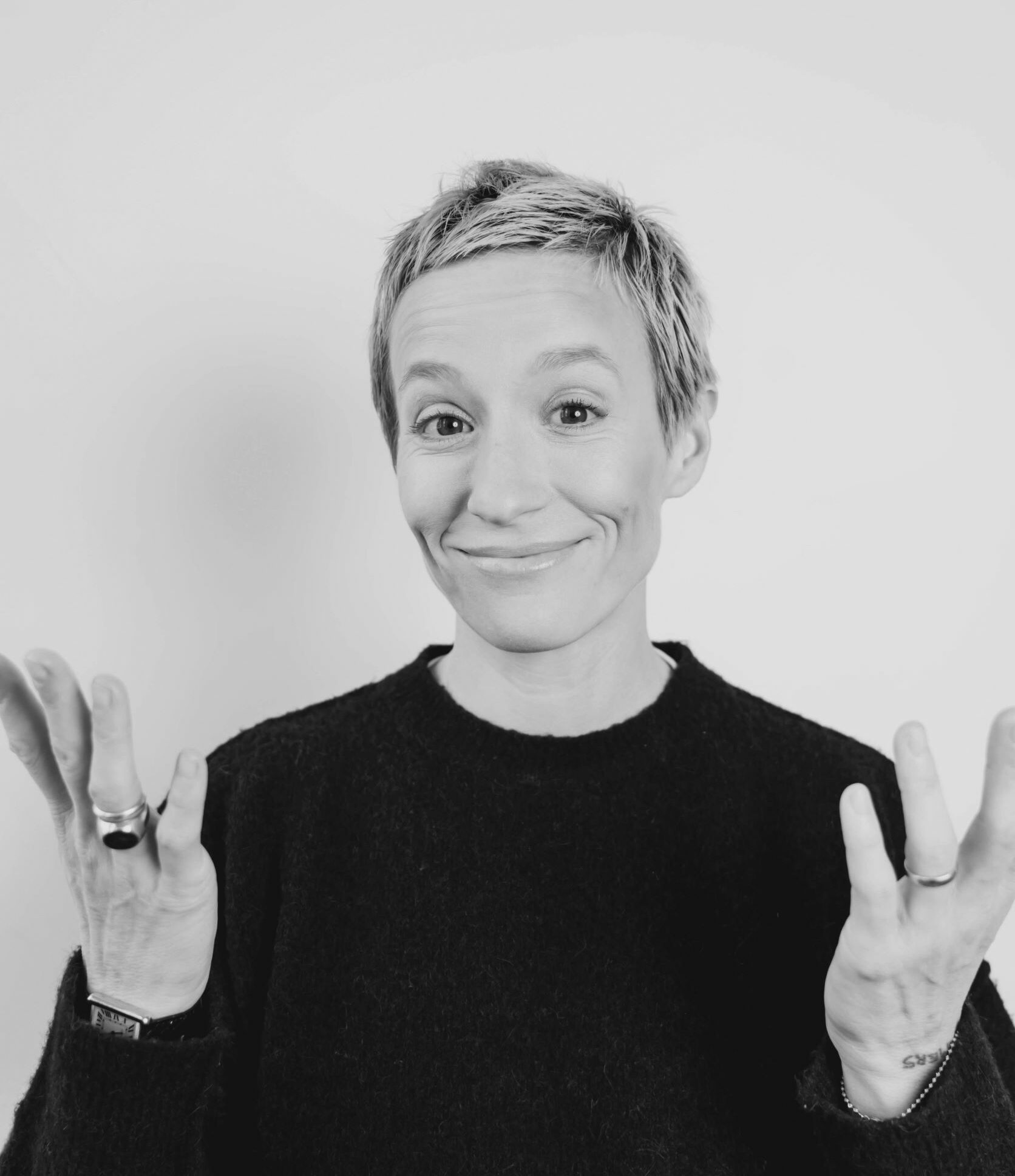 Headshot of Megan Rapinoe with arms lifted in subtle humor.
