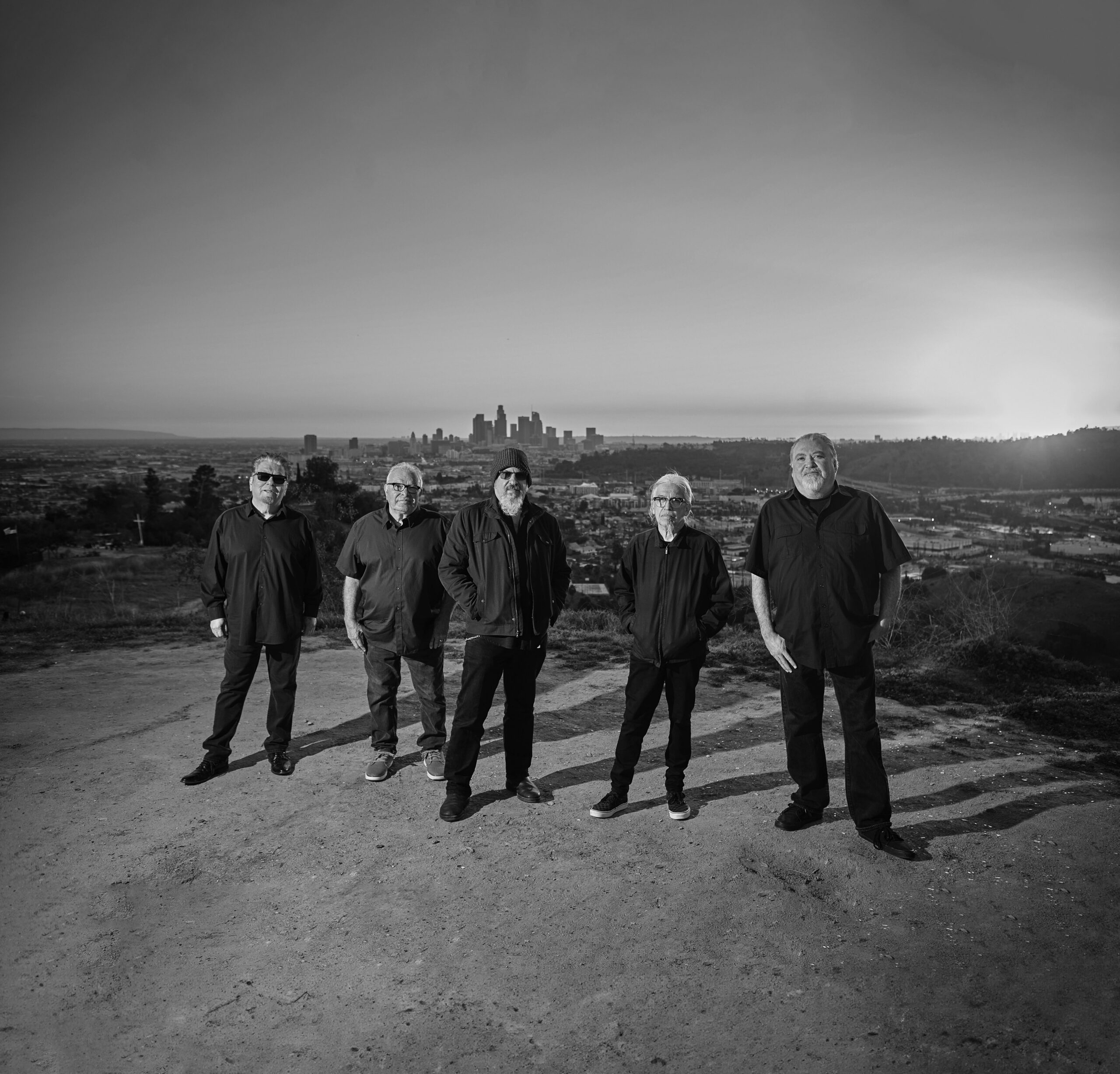 Los Lobos members stand together on a hill overlooking Los Angeles.