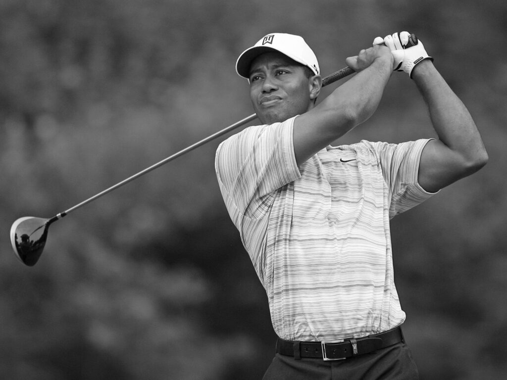 Tiger Woods swinging his golf club and gazing into the distance.