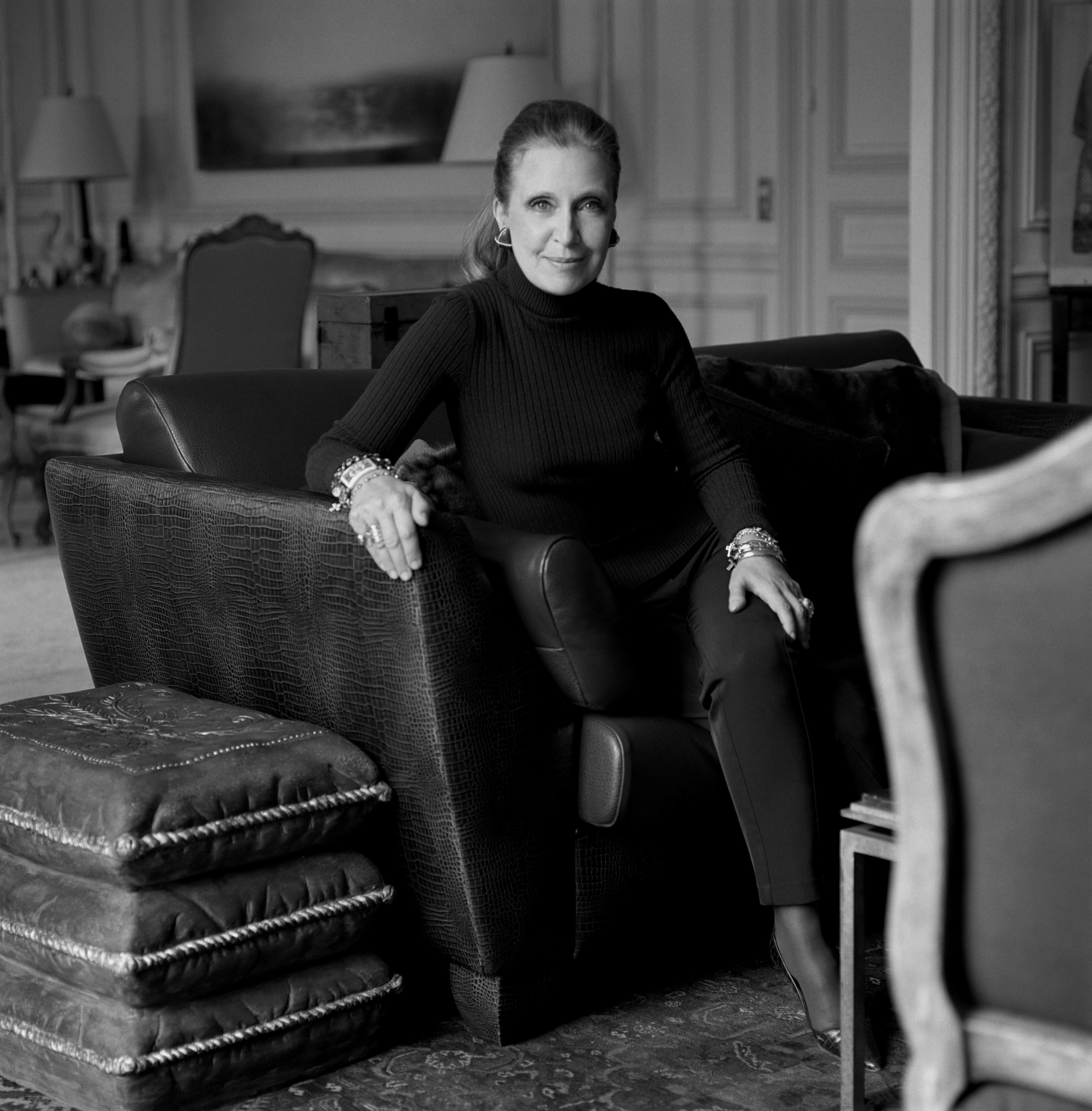 Danielle Steel sits on a leather couch in a fancy room.