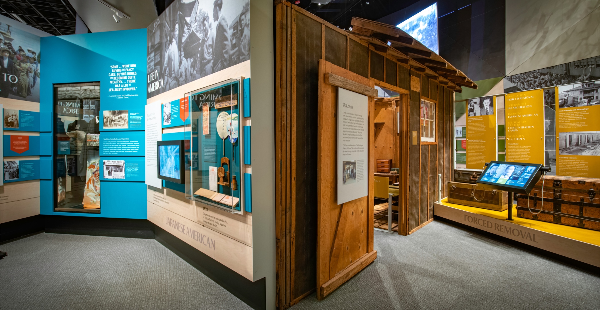 A kimono, hand fans, and model barracks in the Uprooted exhibit.