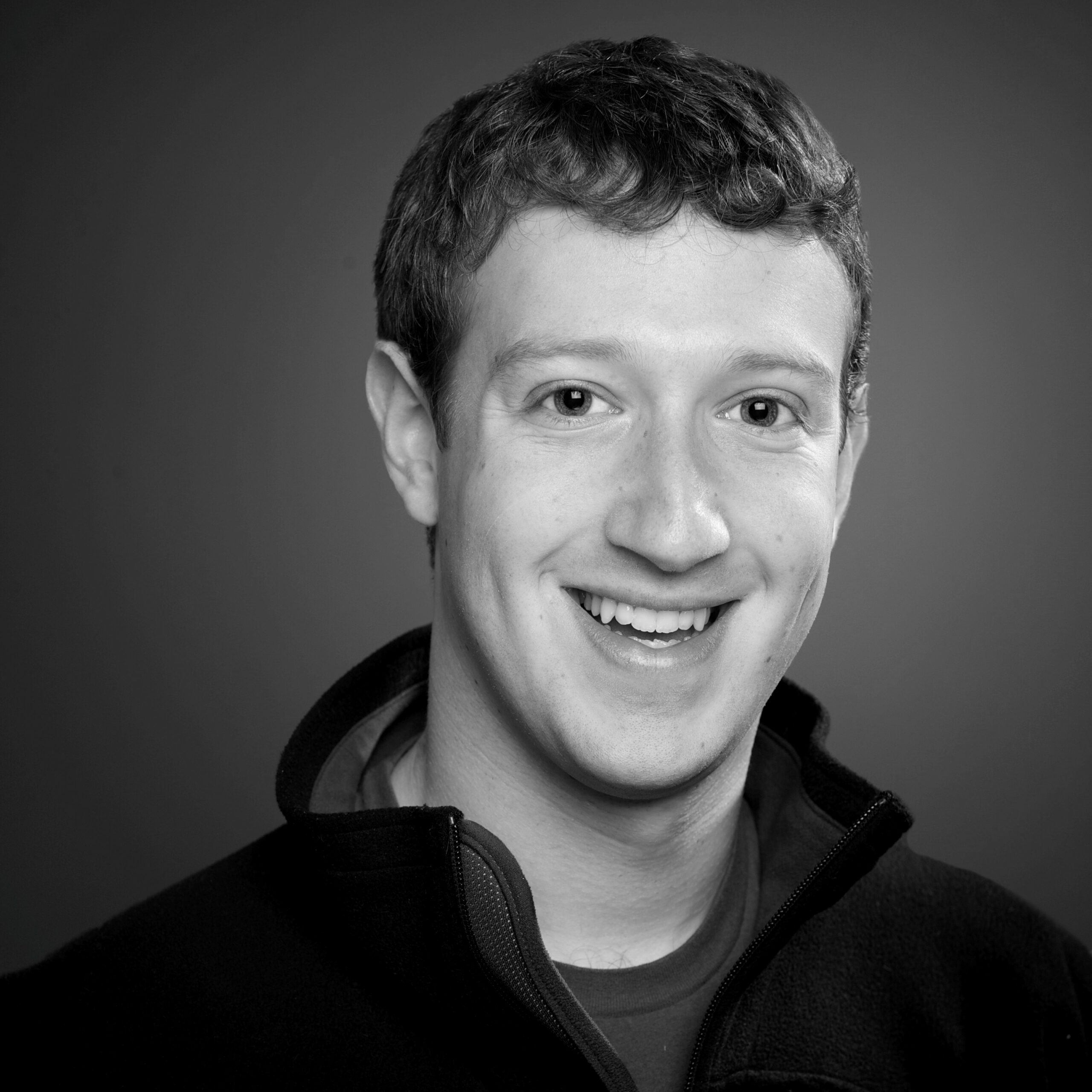 Headshot of a joyful Mark Zuckerberg in a zip-up jacket.