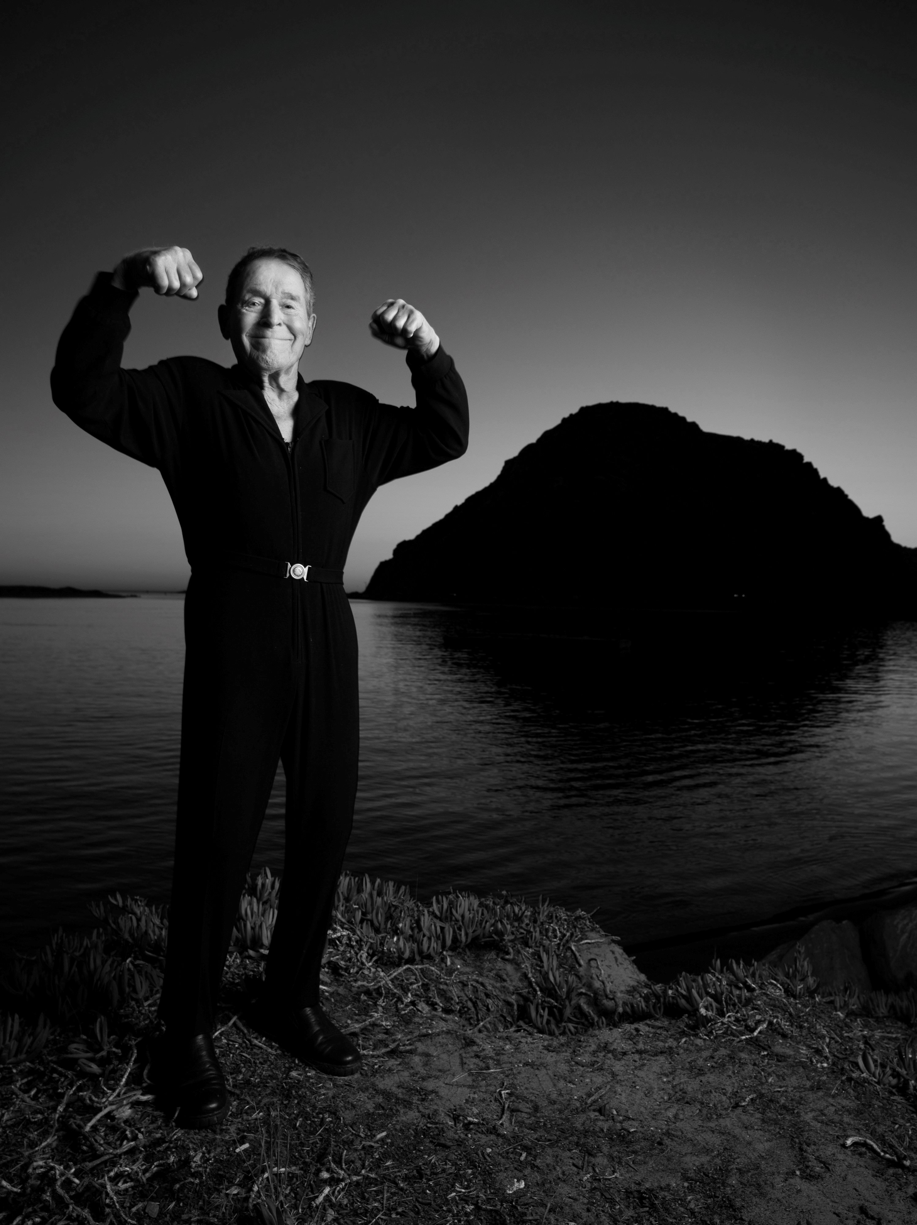 Jack LaLanne poses with arms curled up and biceps flexed.