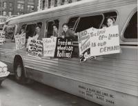 Freedom riders hold signs out of a bus window.