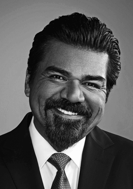 Headshot of George Lopez with slicked back hair wearing a suit.