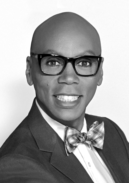 Headshot of a poised RuPaul wearing a tuxedo and thick-rimmed glasses.