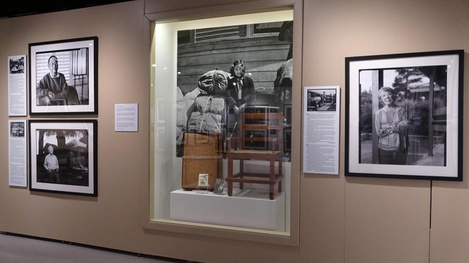 A gallery wall with photos and a chair and suitcase displayed.