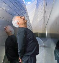 Man looking upward between two reflective walls.