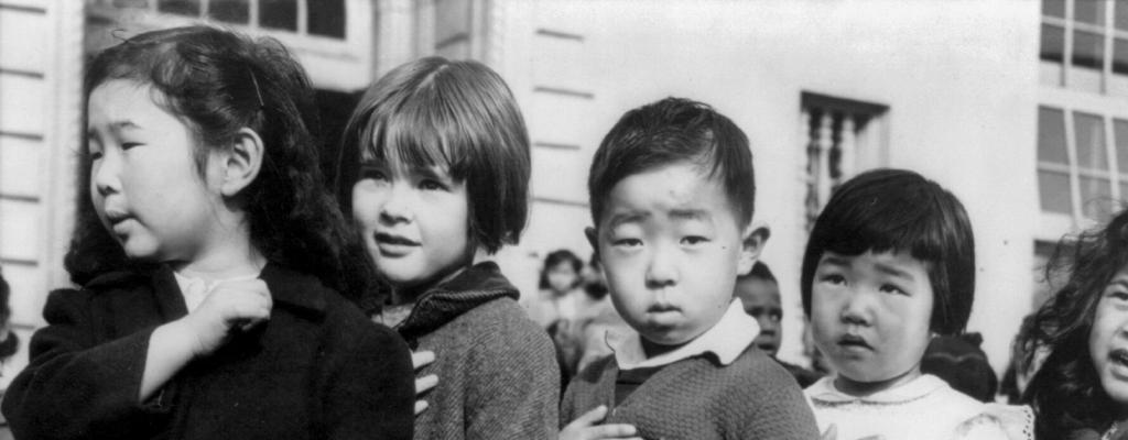 Japanese school children with hands over their hearts.