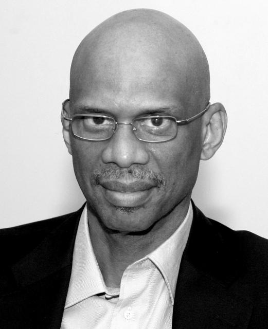 Headshot of Kareem Abdul-Jabbar wearing a suit and small glasses.