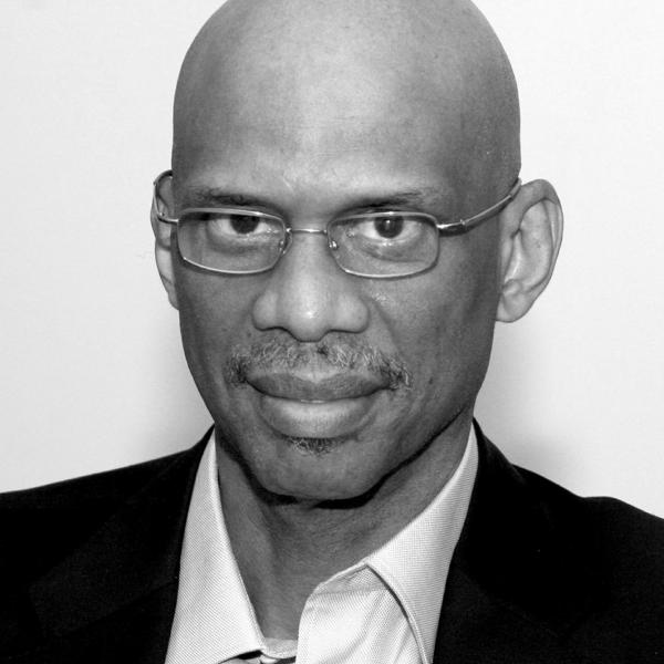 Headshot of Kareem Abdul-Jabbar wearing a suit and small glasses.