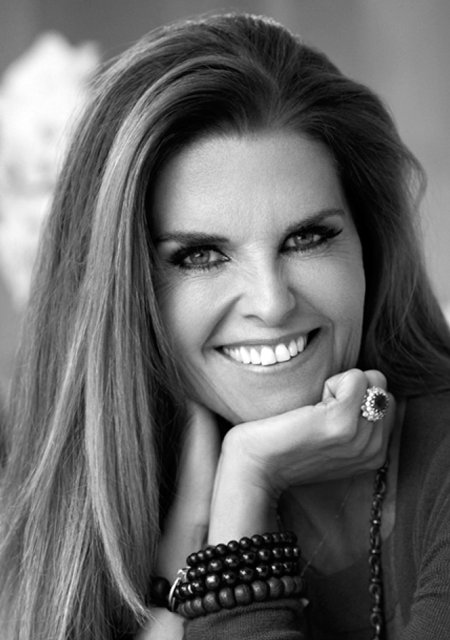 Headshot of a warmly smiling Maria Shriver resting her chin on her palm.