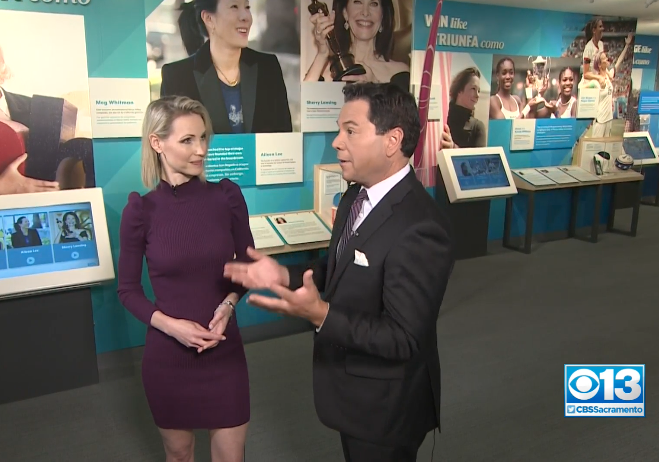 Two CBS 13 reporters in discussion standing in the Women Inspire exhibit.