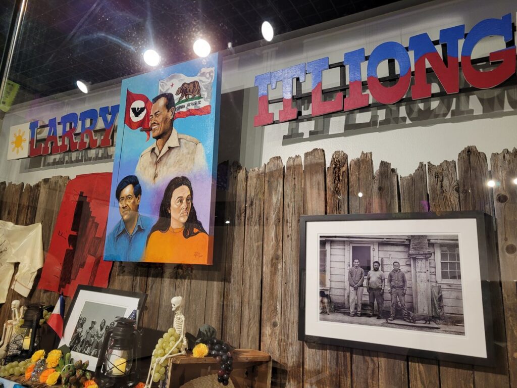 altar with painting of Larry Itliong and other activists, with a backdrop of a wooden fence