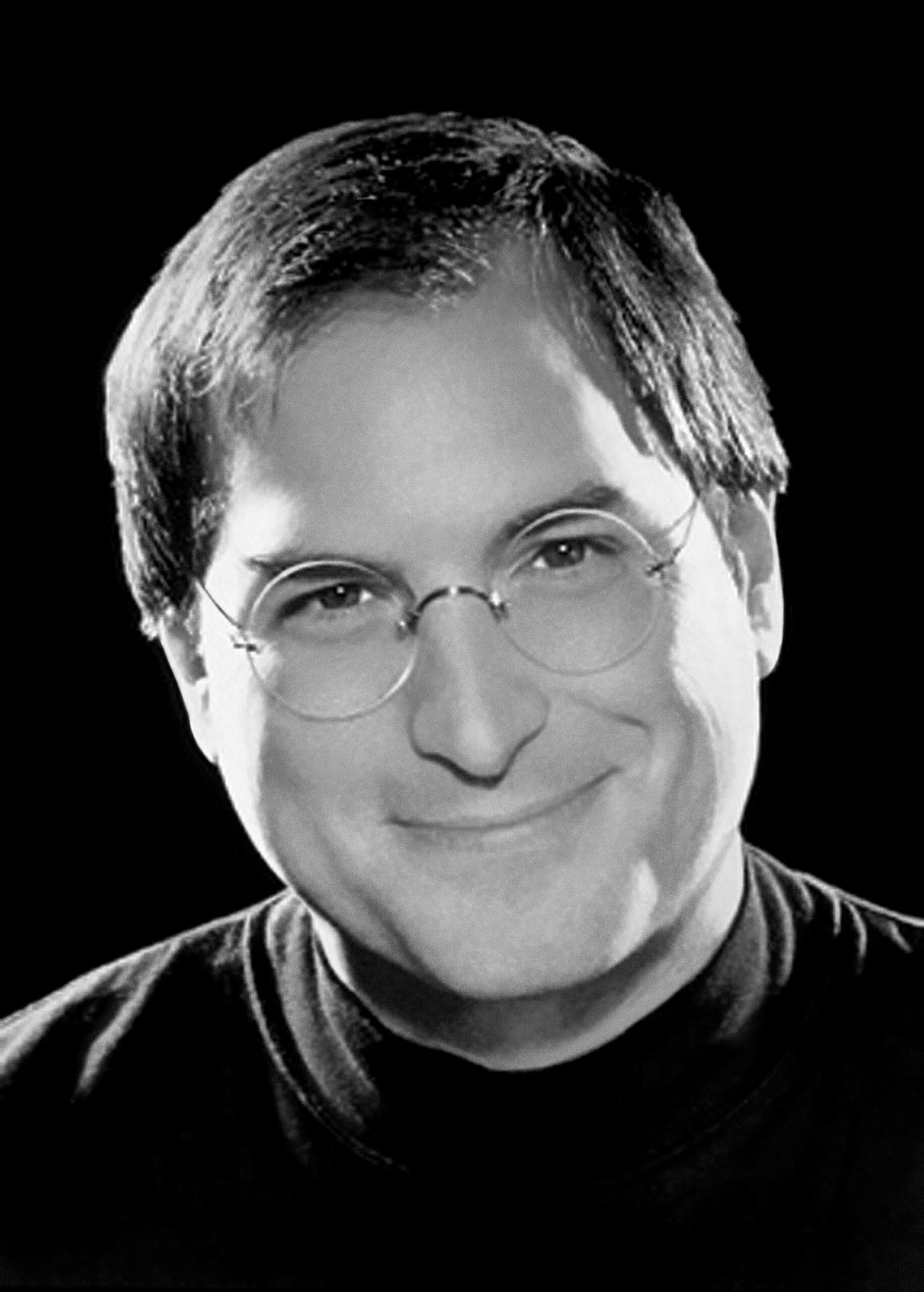 Headshot of a pleasant Steve Jobs wearing his signature turtle neck and round glasses.