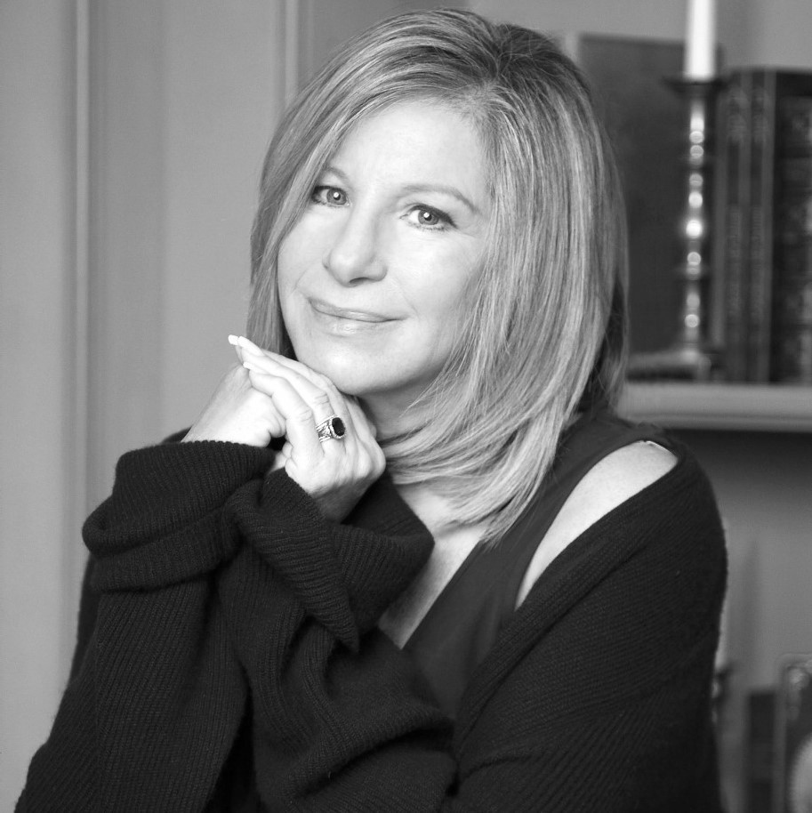 Headshot of Barbra Streisand with a soft smile and hands folded below her chin.