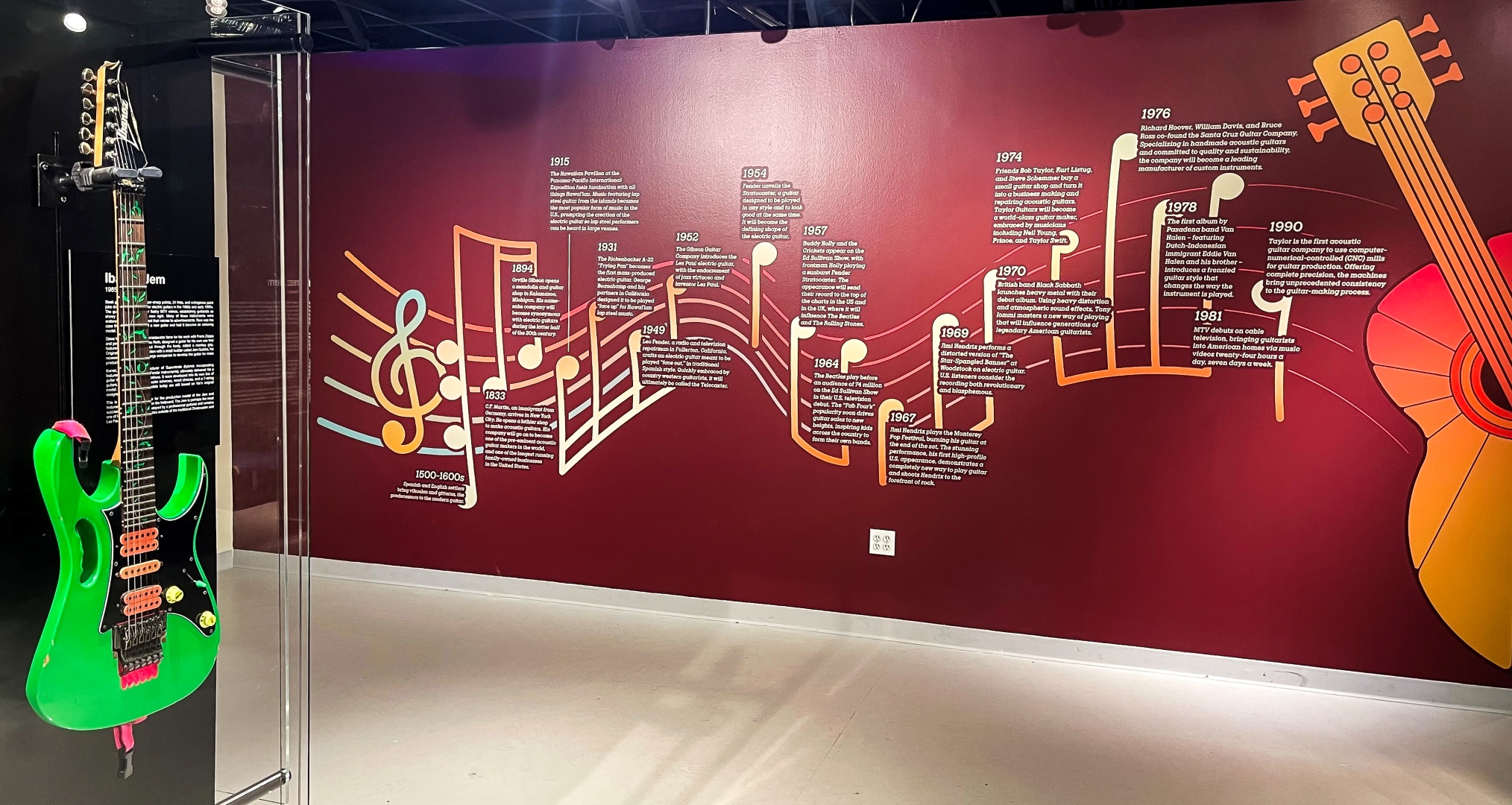 A timeline of guitar history modeled to look like sheet music on a gallery wall.